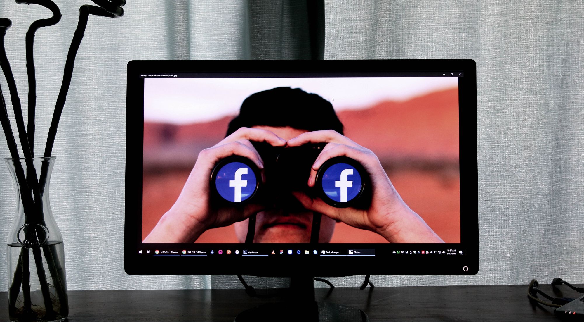 تصویر مردی که از طریق دوربین دوچشمی پوشیده شده با آرم فیس بوک در حال نگاه کردن به کامپیوتر است